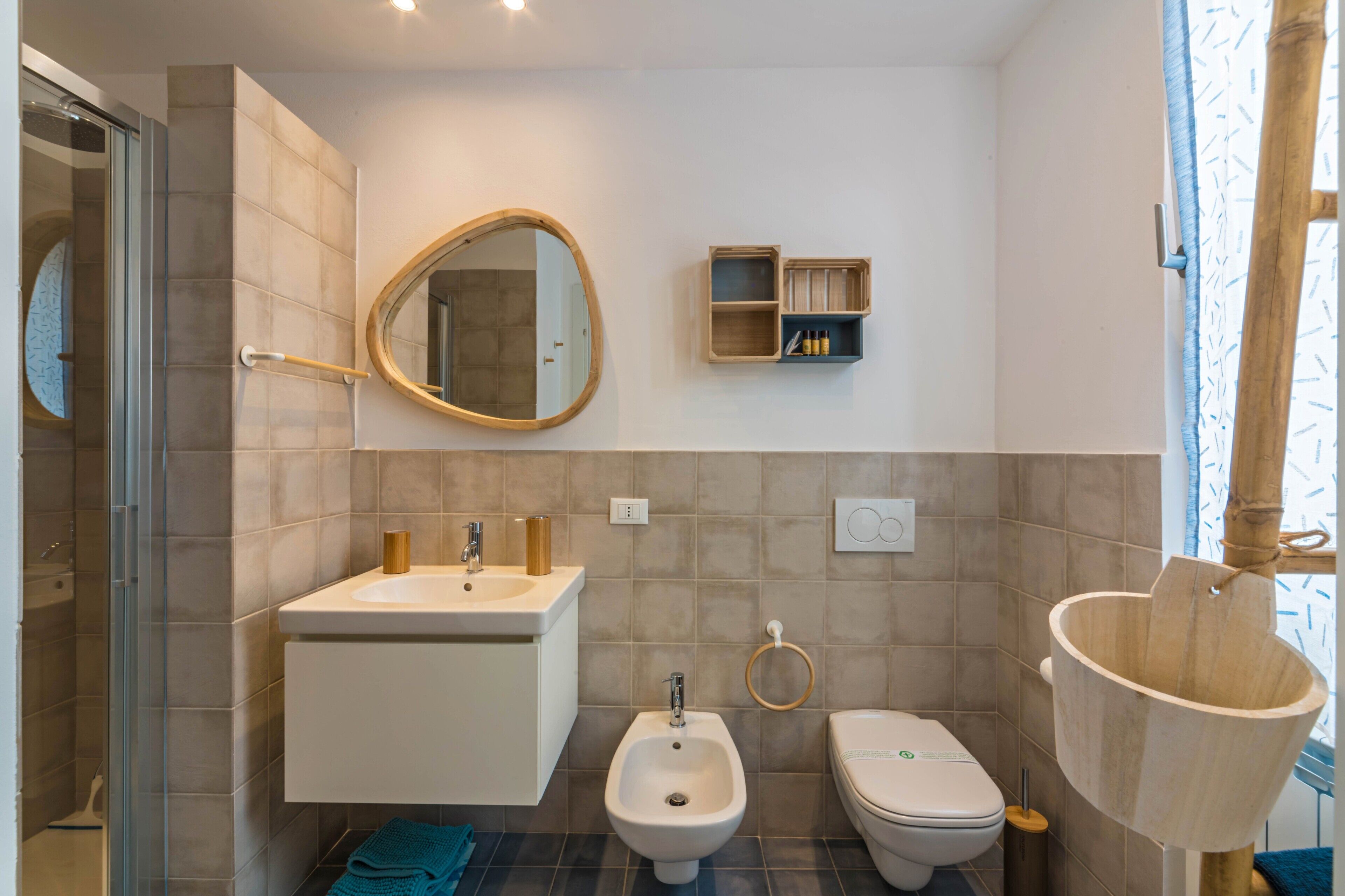 Ein modernes Badezimmer mit Dusche, Bidet, Toilette und einem Holzwaschbecken.