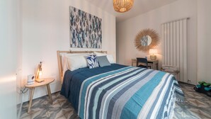 Ein Schlafzimmer mit einem Bett, einem Nachttisch mit Lampe, einem Wandspiegel und einer Heizung.