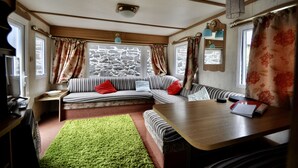 A cozy room with a sofa, a small table, a green rug, and a stone wall. - Ideal rural location for beaches, hills, forests, waterfalls and town (Bow Street)