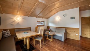 A cozy room with a wooden ceiling, a dining table with chairs, a sofa, and a small table with a flower. - Apartment "Hahndl II" with Mountain View, Wi-Fi, Garden, Terrace and Balcony (St. Leonhard in Passeier Südtirol)