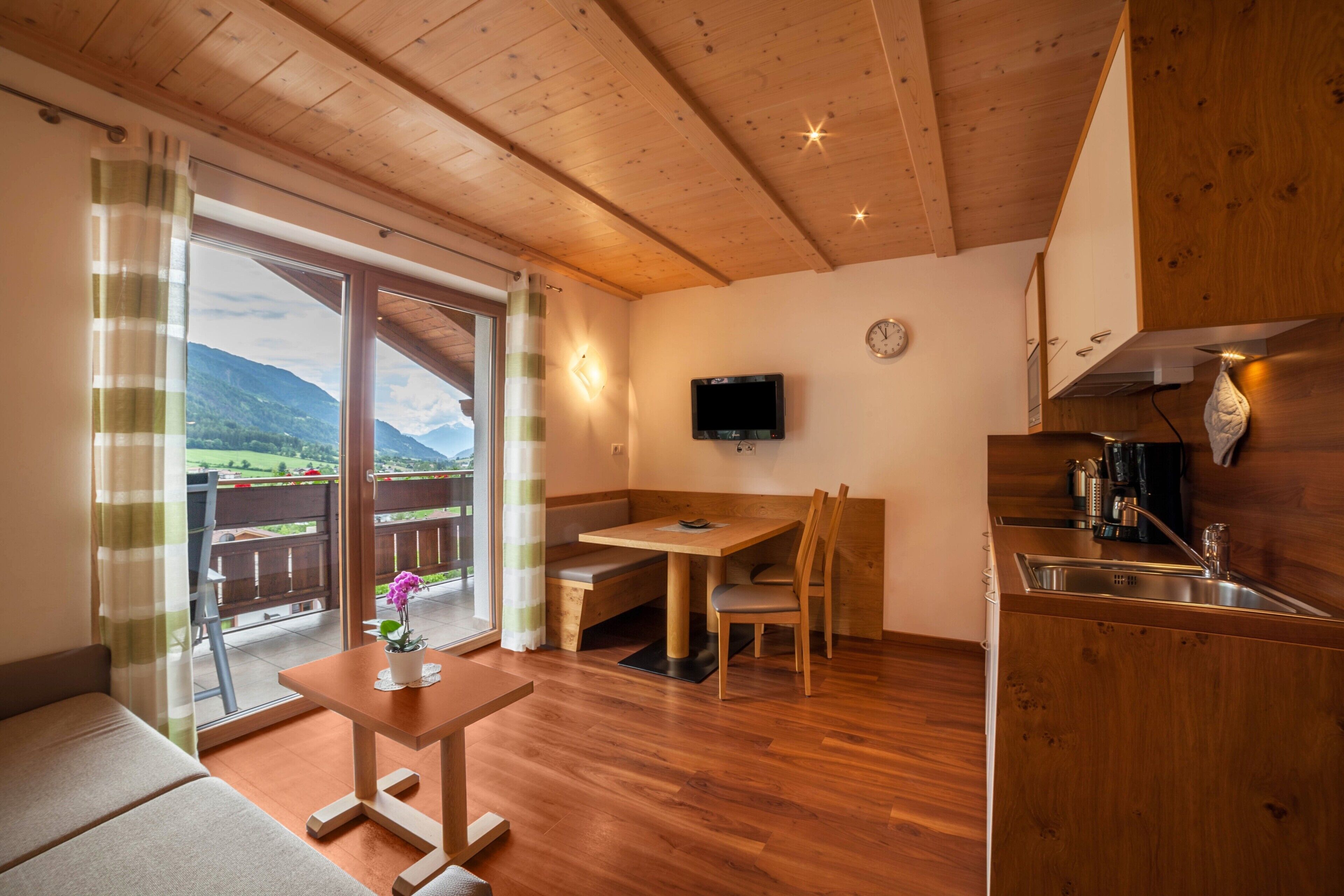 A wooden interior with a dining area, a kitchen, and a balcony with a view.