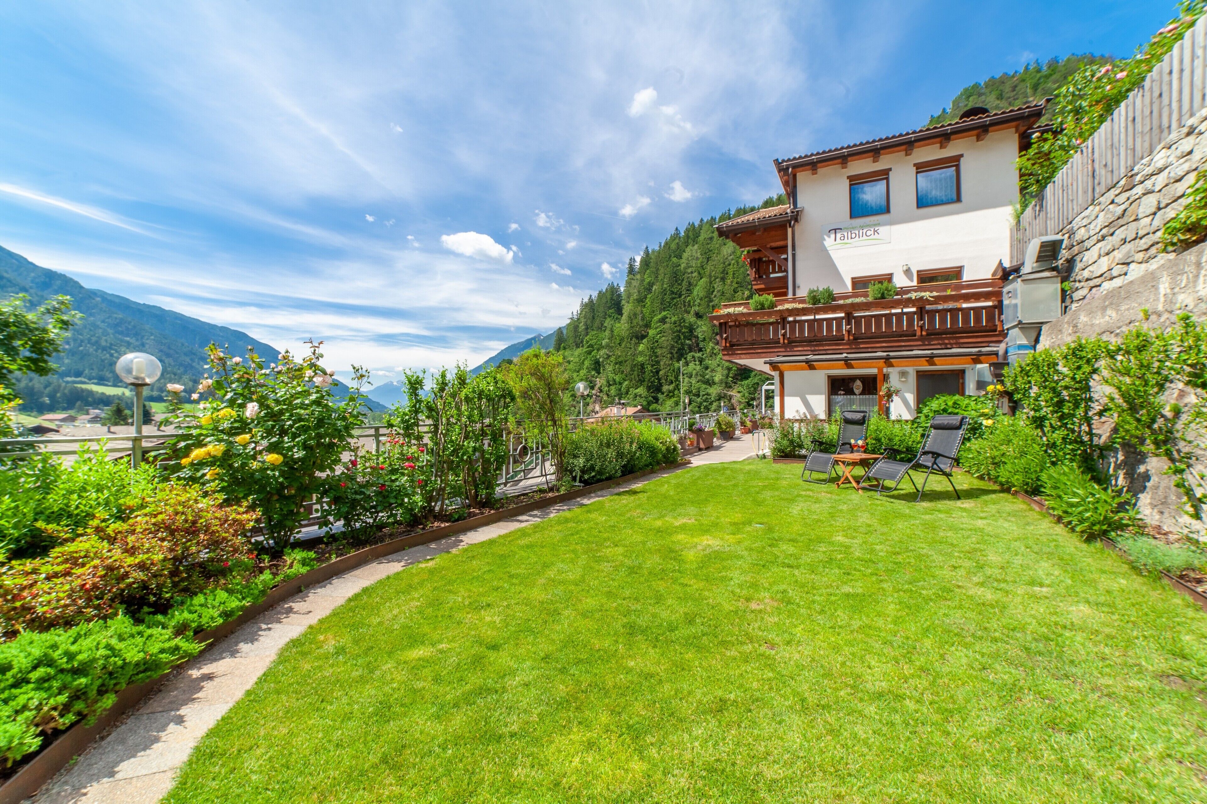 Une propriété offrant une vue sur les montagnes, dotée d’une pelouse bien entretenue, d’un espace salon extérieur et d’un balcon avec vue.