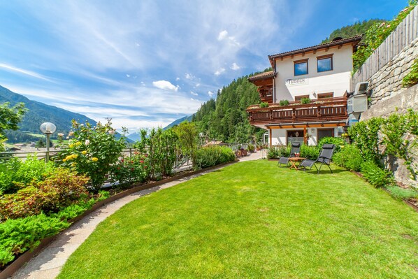 A mountain-view property with a well-maintained lawn, outdoor seating, and a balcony with a view.
