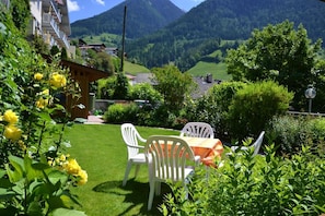 Une terrasse avec une table et des chaises, entourée de verdure et offrant une vue sur la montagne.