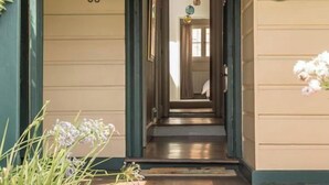 A building entrance with a number '36' on the wall, a wooden door, and a small garden area with plants. - Luxury Villas The Secret Garden (Pet Friendly) (Melbourne)