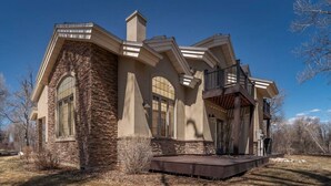 Une maison moderne avec une façade en pierre, de grandes fenêtres et un balcon.