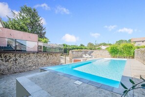 A swimming pool with a stone wall and a glass-enclosed area. - Retreat in Saint Denis (Saint-Denis)