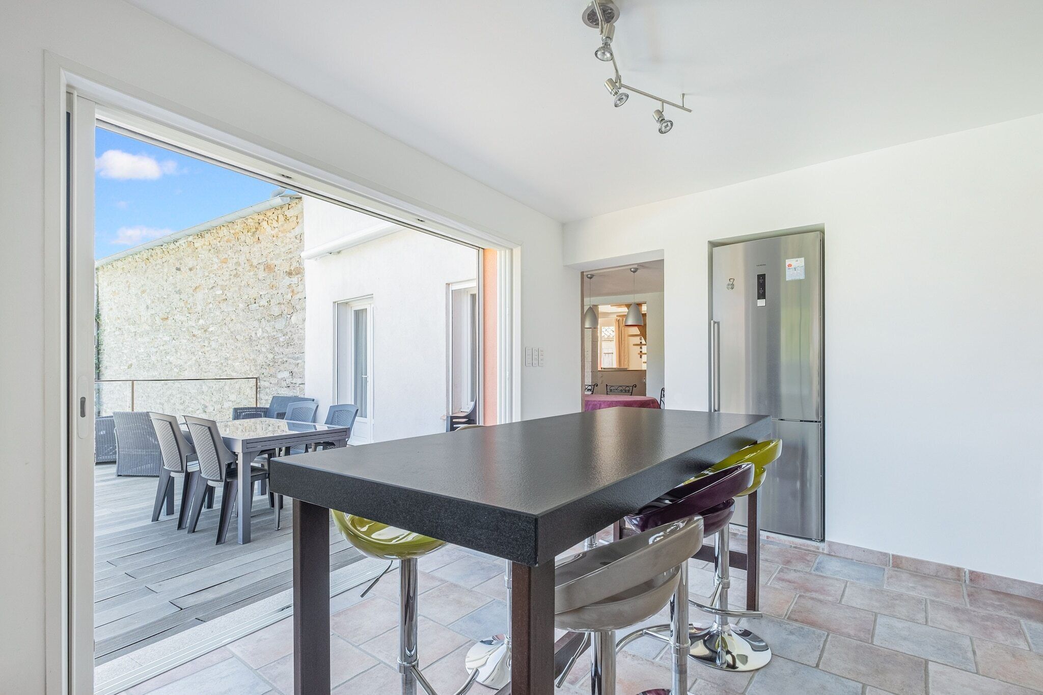A modern kitchen with a large island, stainless steel appliances, and a view to an outdoor patio area.