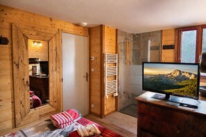 A wooden room with a bed, a TV, and a shower area. - CHARMING CHALET, MOUNTAIN VIEW AND SKI SLOPES JACUZZI HAMMAM SAUNA TABLE SOCCER (Vars)