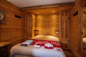 A wooden room with a bed, a clock, and a wall-mounted light fixture. - CHARMING CHALET, MOUNTAIN VIEW AND SKI SLOPES JACUZZI HAMMAM SAUNA TABLE SOCCER (Vars)