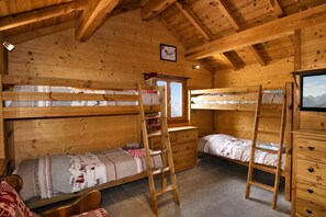Eine Holzhütte mit Etagenbetten, einer Leiter, einem Schmuckkästchen und einem Fenster mit Blick.