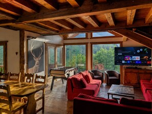 A cozy living room with a wooden ceiling, a foosball table, red sofas, and a television. - CHARMING CHALET, MOUNTAIN VIEW AND SKI SLOPES JACUZZI HAMMAM SAUNA TABLE SOCCER (Vars)