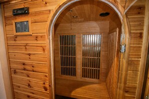 Eine Holzsauna mit Bedienfeld, zwei Lüftungsfenstern und einer Tür.