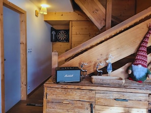 A wooden interior with a dartboard, a small speaker, and a gnome decoration.