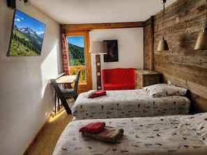 A hotel room with two beds, a desk, a chair, a red sofa, a wooden wall, and a painting. - CHARMING CHALET, MOUNTAIN VIEW AND SKI SLOPES JACUZZI HAMMAM SAUNA TABLE SOCCER (Vars)