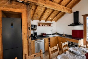 Eine Küche mit Holzbalken, einem Kühlschrank, einer Mikrowelle, einem Spülbecken und einem Herd.