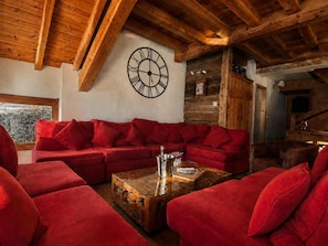 Una habitación acogedora con un sofá seccional rojo, una mesa de centro de madera y un gran reloj de pared.