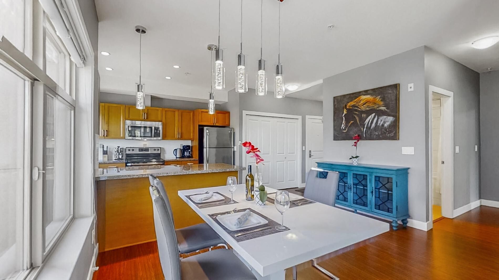A modern kitchen with wooden cabinets, stainless steel appliances, and pendant lighting.