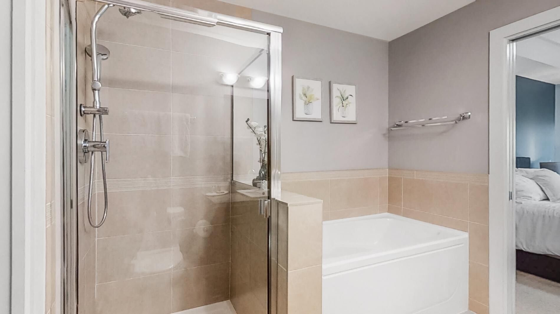 Un baño moderno con ducha envuelta en vidrio, una bañera independiente y dos obras de arte enmarcadas en la pared.