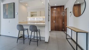 A modern kitchen with a white countertop, two grey bar stools, and a wooden door. - Modern 5B villa in El Duque, heated pool, wifi, just 250m from the beach (Costa Adeje)