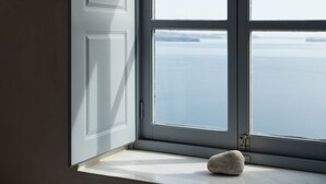 Una habitación con ventana que da a una masa de agua, un cuenco de madera en el alféizar y una puerta con manija.