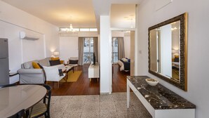 Una sala de estar moderna con comedor, un espejo grande y vista al balcón.