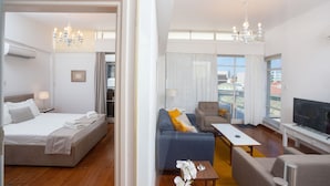 Una habitación de hotel con cama, sofá, televisión y balcón con vistas.