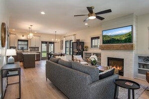 A modern living room with a fireplace, sofa, dining area, and kitchen.