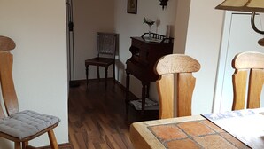 Ein Essbereich mit Holzmöbeln, einem Klavier und einer Wanduhr.