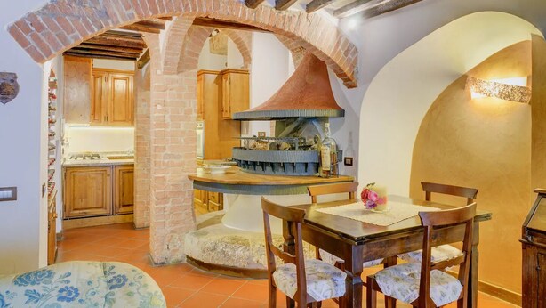 Una cocina rústica con arcos de ladrillo visto, armarios de madera y un horno de pizza empotrado.