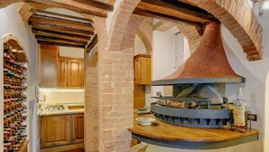 Una cocina con armarios de madera, una estantería para vinos y una estufa de cobre grande.