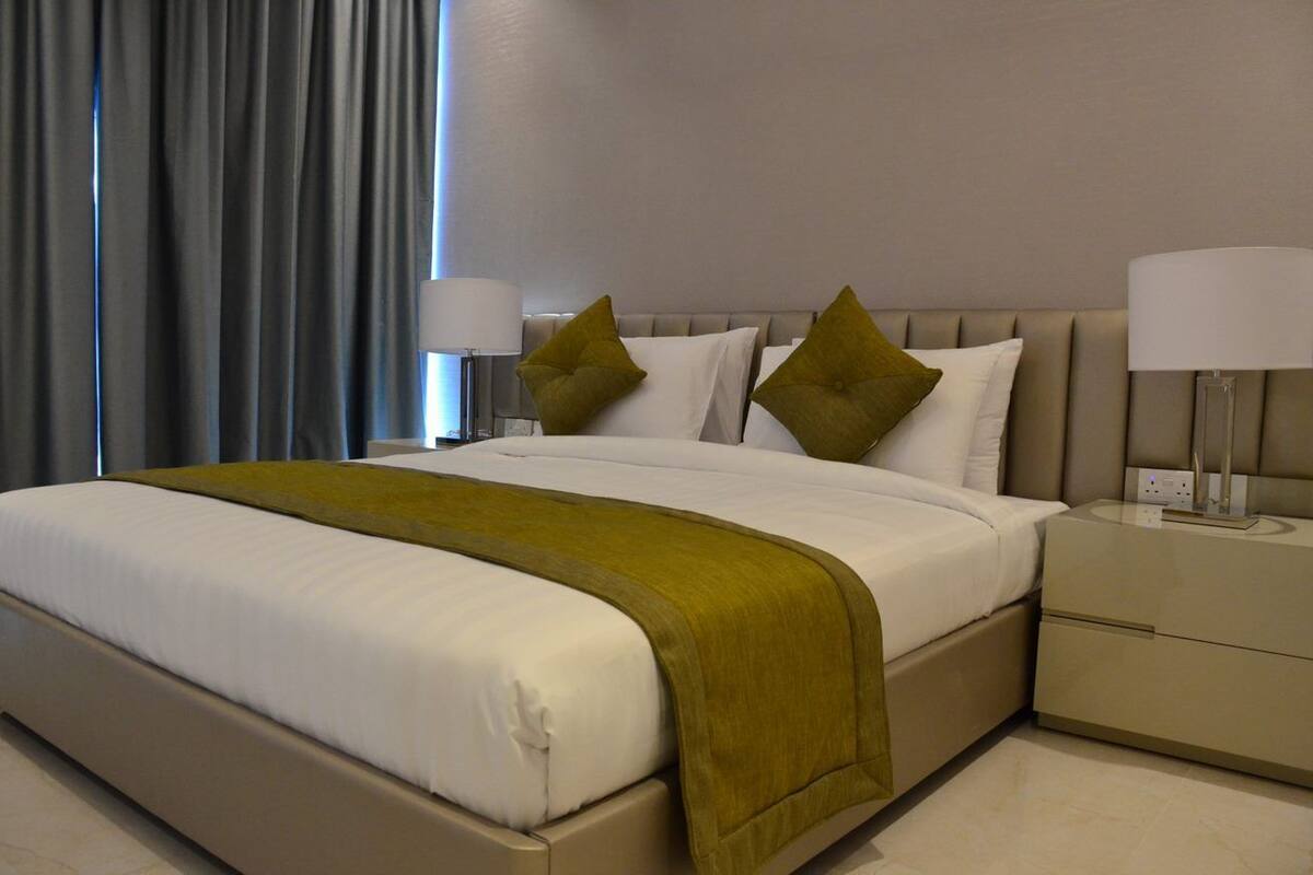 A hotel room with a large bed, two bedside tables with lamps, and a window with curtains.