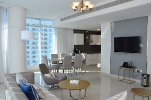 A modern hotel room with a living area, dining space, and kitchen. - The Lodge Suites (Manama)