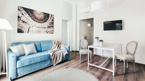 Ein modernes Wohnzimmer mit einem blauen Sofa, einem weißen Couchtisch und einem großen Gemälde an der Wand.