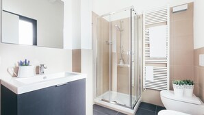 Ein modernes Badezimmer mit einer Duschkabine aus Glas, einem weißen Waschbecken und einer Toilette.