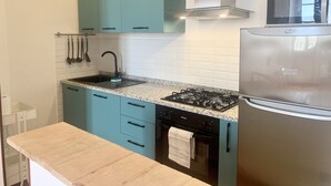Une cuisine moderne avec des armoires de couleur turquoise, un comptoir en granit, un réfrigérateur en acier inoxydable, une cuisinière à gaz et un four à micro-ondes.