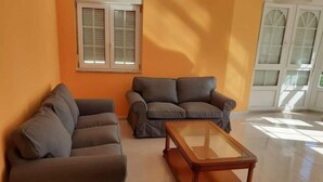 Una sala de estar con dos sofás y una mesa de centro de vidrio.