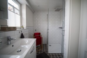 A bathroom with a white sink, a glass shower enclosure, and a patterned floor.