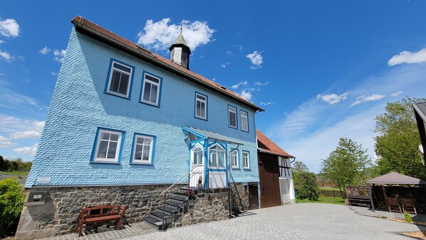 A two-story building with a blue exterior and a stone foundation.