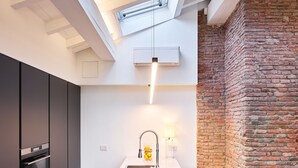 A modern kitchen with a central island, built-in appliances, and a brick accent wall.