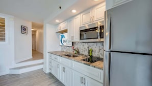 A modern kitchen with white cabinets, stainless steel appliances, and a tiled backsplash. - Oceanfront condo with pool & hot tub access (North Myrtle Beach)