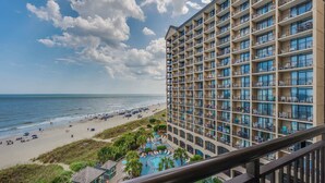 A high-rise hotel with multiple balconies overlooking a beach and ocean. - Oceanfront condo with pool & hot tub access (North Myrtle Beach)