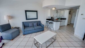 Un salon moderne avec un canapé, une table basse et un coin cuisine à l’arrière-plan.