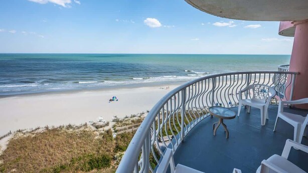 Un balcon avec vue sur la plage et l’océan.