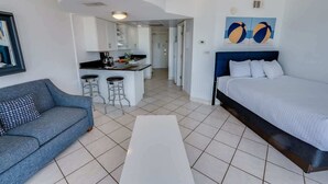 Une chambre d’hôtel moderne comprenant un lit, un canapé, un petit coin cuisine et un espace repas.