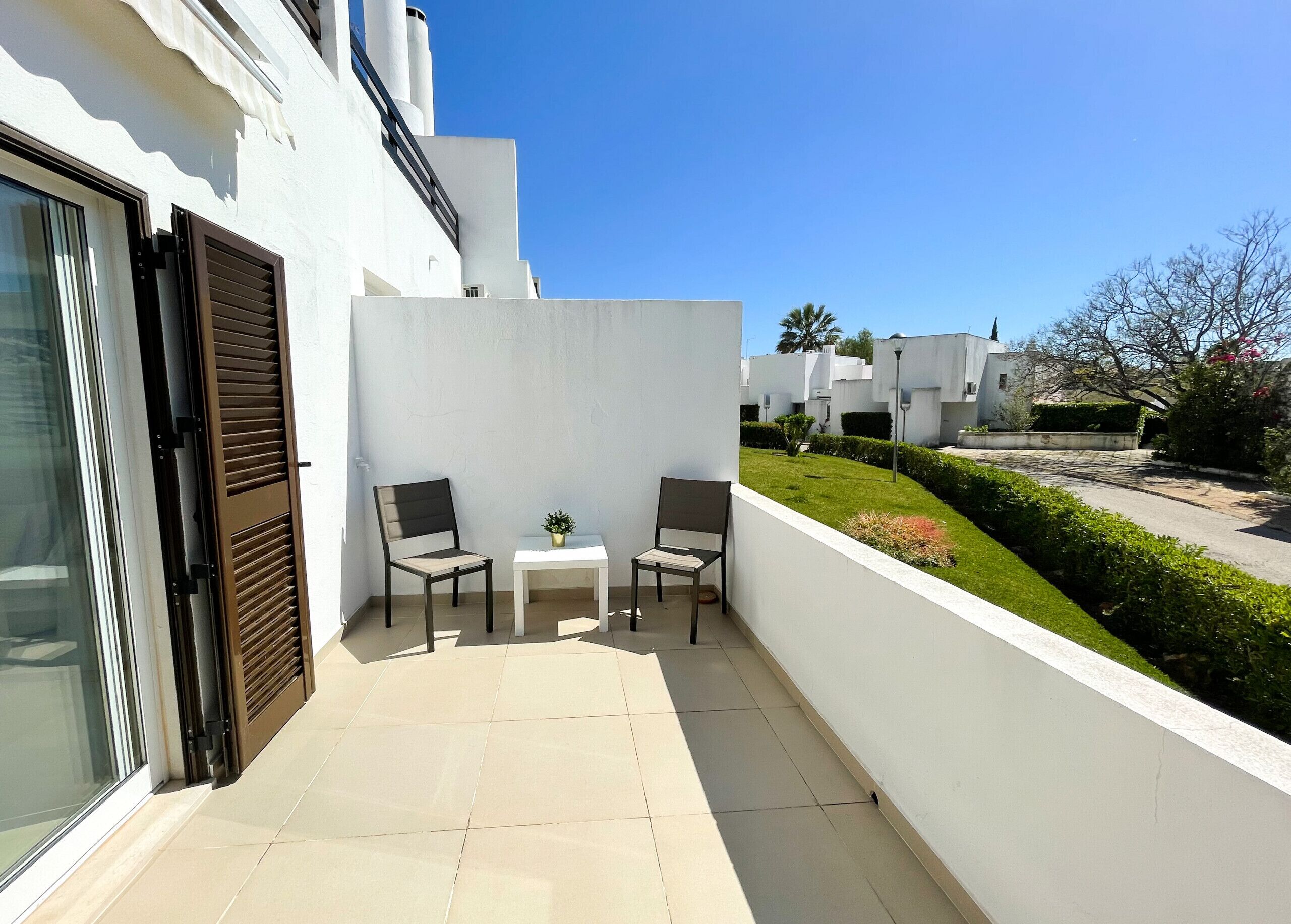 Un balcon avec deux chaises, une petite table et un pot de fleurs.