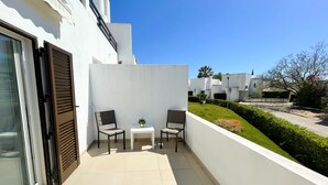 A balcony with two chairs, a small table, and a potted plant. - Casa Rosa - Vilamoura (Vilamoura)