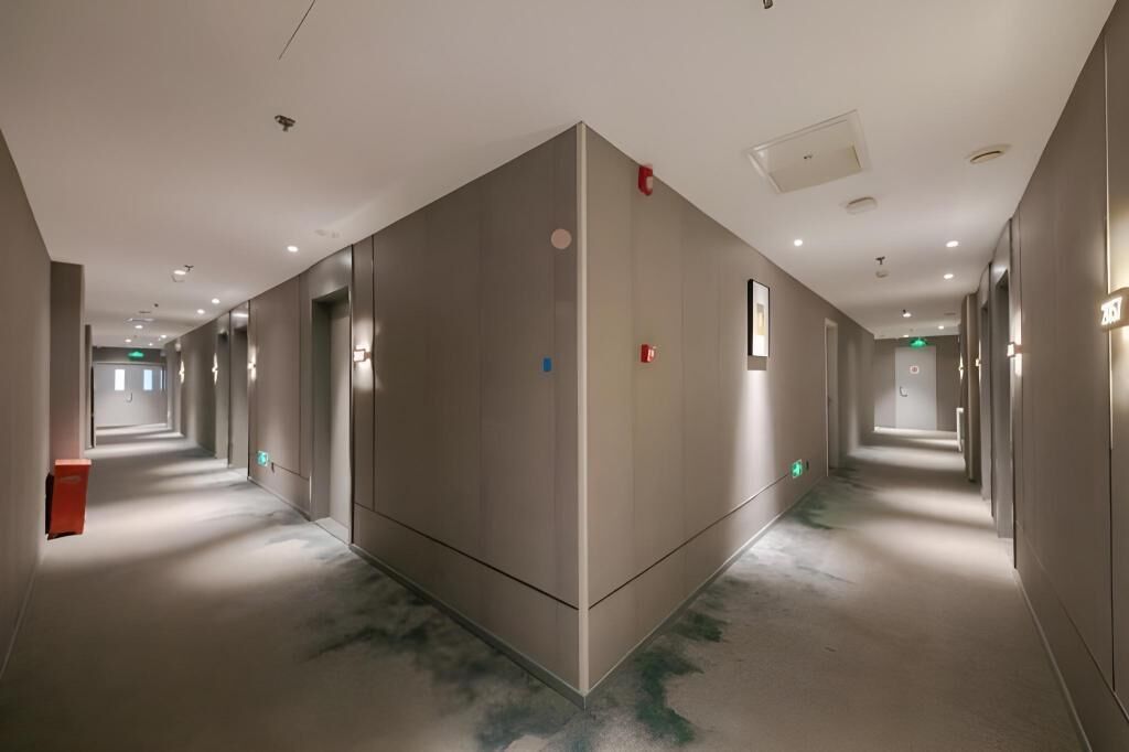 Un pasillo moderno de hotel con un ascensor central, iluminación empotrada y un diseño limpio y minimalista.