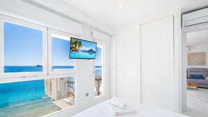 A hotel room with a bed, a TV, and a view of the sea.