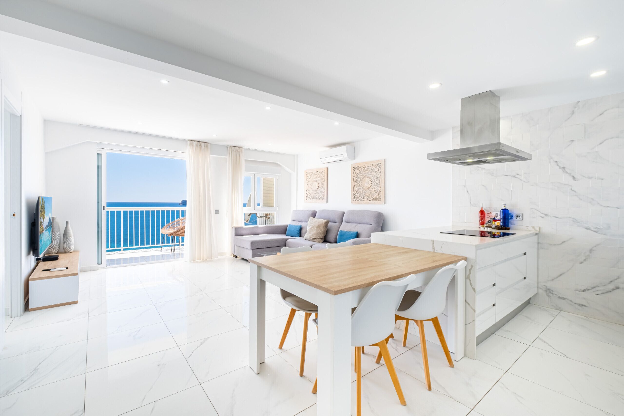 A modern living room with a dining area, a sofa set, and a kitchen with marble walls.
